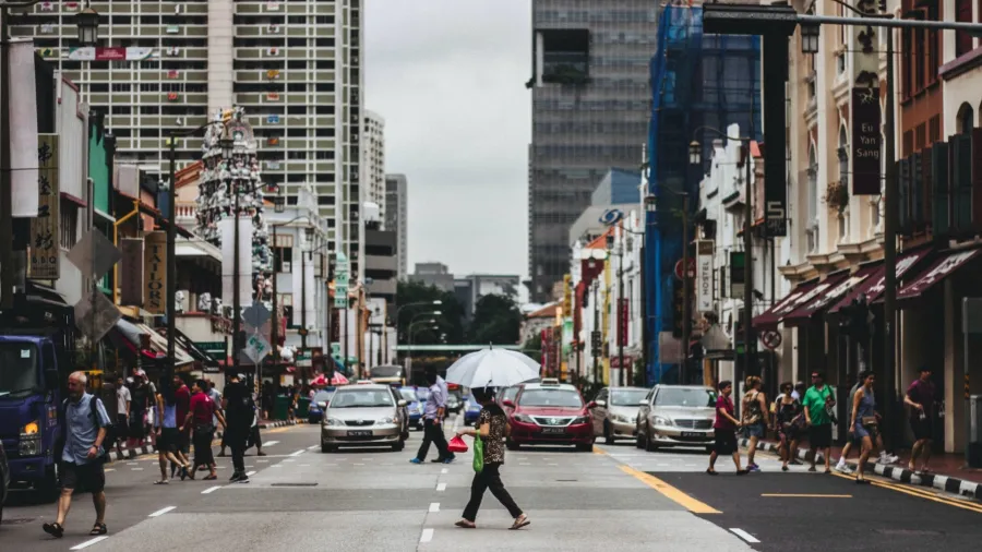 A woman crossing a street in Singapore (Photo by Lily Banse via Unsplash).