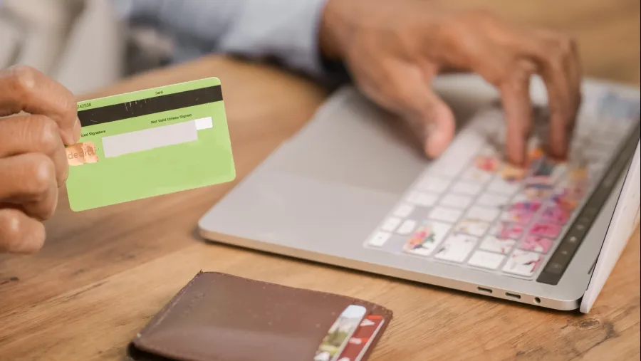 Photo by Kindel Media: https://www.pexels.com/photo/person-holding-green-card-while-using-silver-laptop-6995134/
