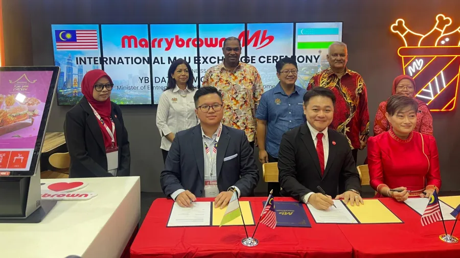 Dato' Joshua Liew (seated middle), Group Executive Director of Marrybrown together with Mr C.Y Pang (seated left), Marrybrown Franchisee – Uzbekistan and Ms. Teh Chui Hoon (seated right), Marrybrown Franchisee – Cambodia during the MoU signing of Marrybrown's new outlet openings in Uzbekistan and Cambodia, witnessed by (from left) YBhg. Dato’ Sri Suriani Binti Dato’ Ahmad, Ketua Setiausaha KUSKOP; YB Dato' Ramanan Ramakrishnan, Timbalan Menteri KUSKOP; YB Datuk Ewon Benedick, Menteri KUSKOP; and YBhg. Datuk Dr. Radzali Hassan, Pengerusi Persatuan Francais Malaysia (MFA).