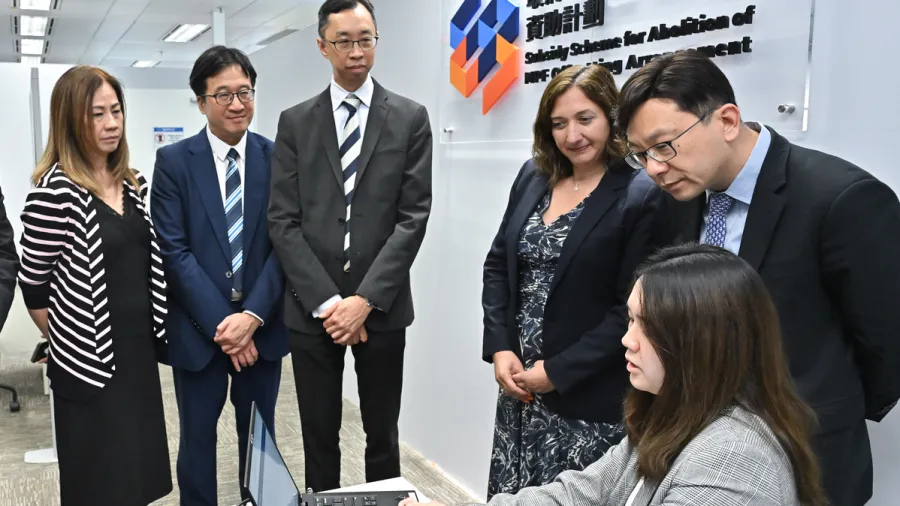 Secretary for Labour & Welfare Chris Sun (second right) watches a demonstration of how employers may submit applications for the Subsidy Scheme for Abolition of MPF Offsetting Arrangement through the TransitionEase Portal.